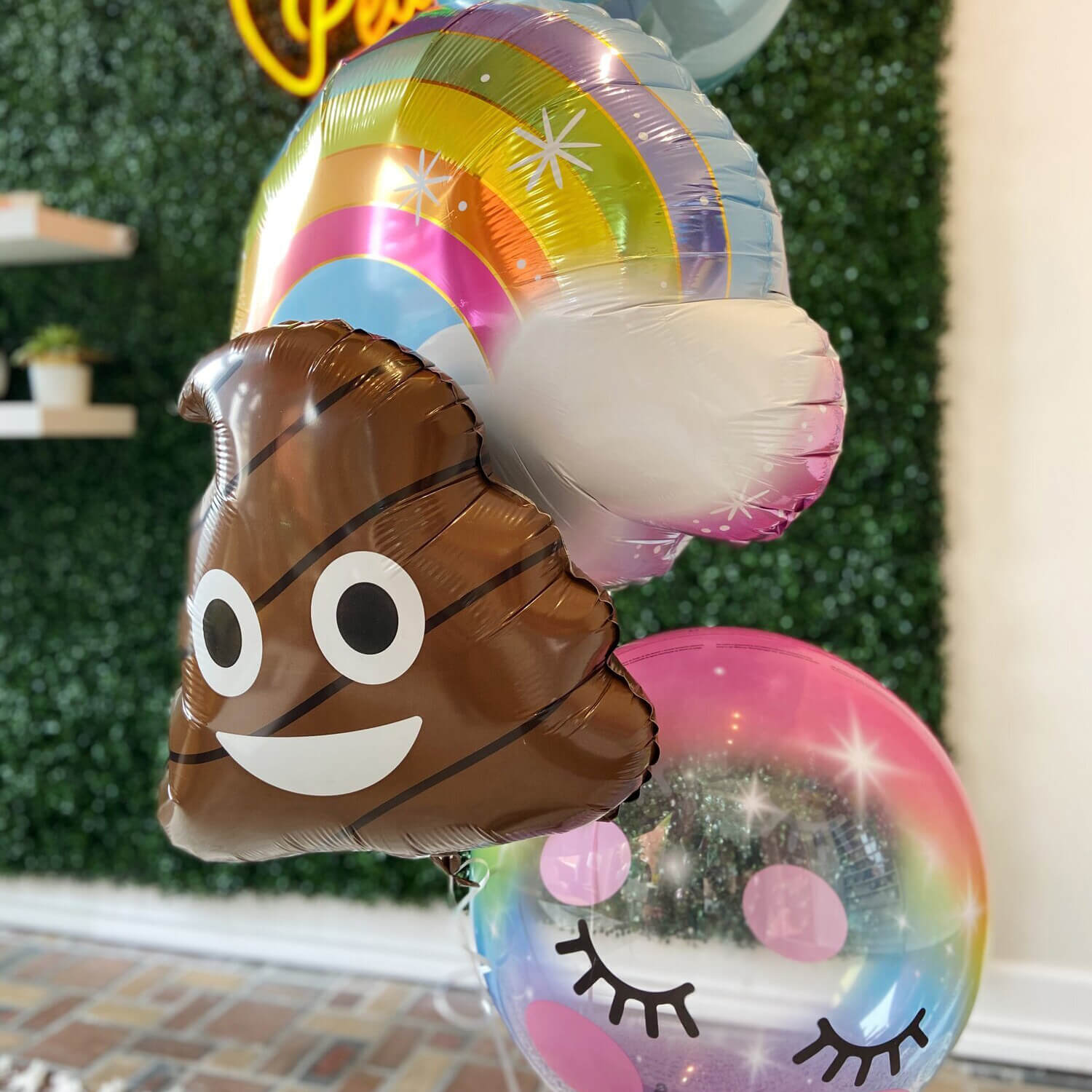 Oversized helium bouquet with poop emoji, pastel rainbow, light blue orb and smiling eyelash bubble balloons from Just Peachy in Little Rock, Arkansas