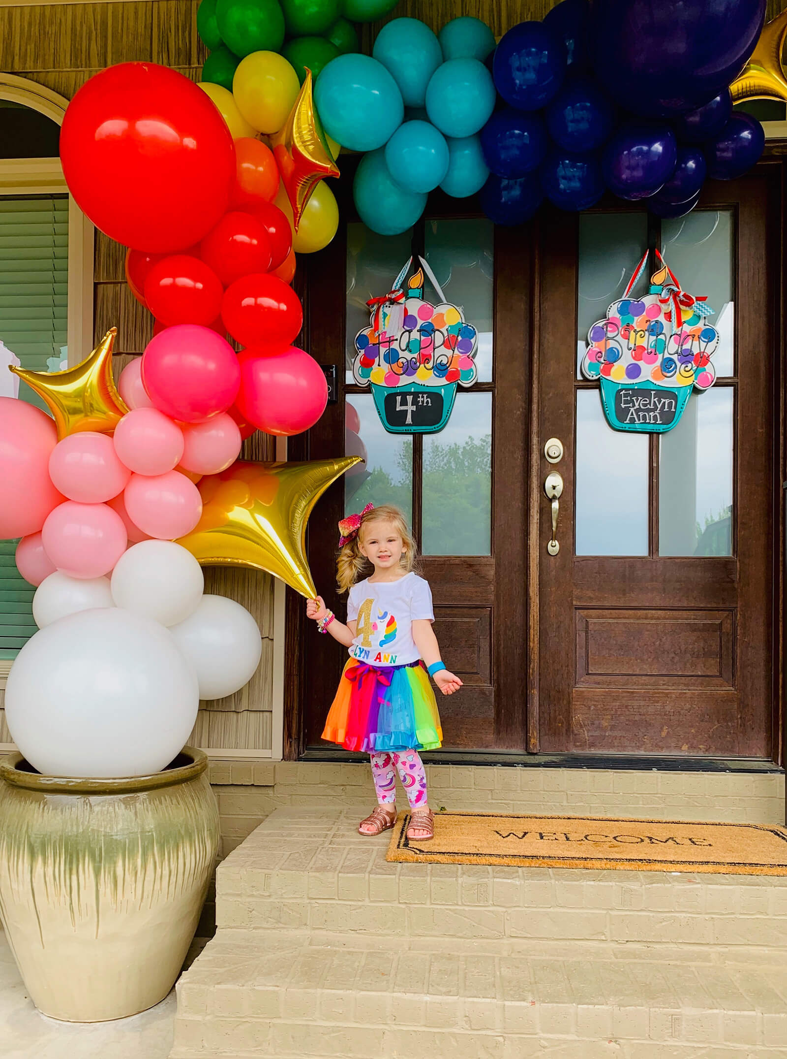 For this 4th birthday we made a rainbow front door display balloon arch installation - Just Peachy in Little Rock, Arkansas.
