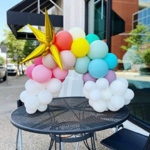 Mini rainbow balloon arch with pink, light blue, soft green, lavender and coral balloons available from Just Peachy in central Arkansas.