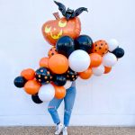 Orange, black, white, and polka dot balloons in a Halloween garland with a giant Jack-O-Lantern on top from Just Peachy≥