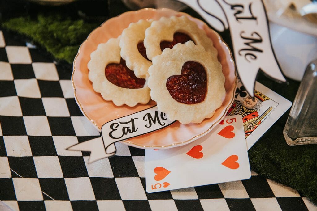 Cut out jelly heart cookies on a checkered tablecloth for an Alice in Wonderland birthday planned by Just Peachy.